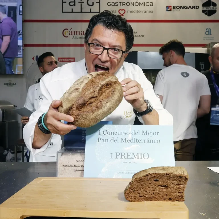 Harinas La Encarnación patrocina el Concurso al Mejor Pan del Mediterráneo con Harina de Algarroba, celebrado en Alicante Gastronómica Carlos Mariu con pan grande y sonriendo, tras lograr el primer premio en el Concurso al Mejor Pan del Mediterráneo con Harina de Algarroba
