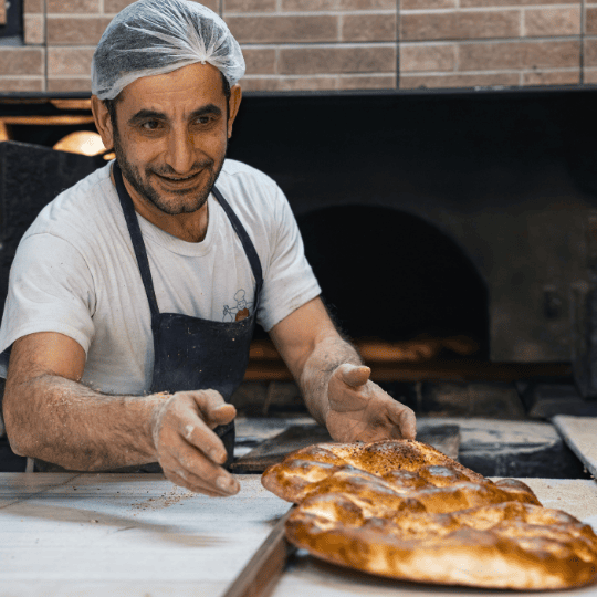 Harinas La Encarnación para cada tipo de pan Panadero sonriente sirviendo pan recién horneado en una panadería.