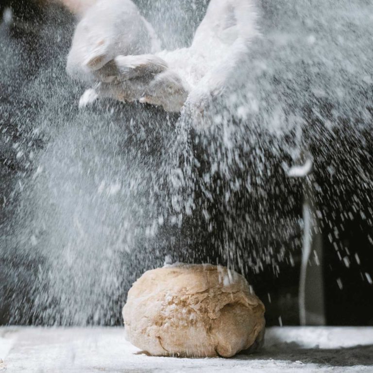 Masa con Harina La ENCARNACION Sin Gluten Manos espolvoreando harina SIN GLUTEN sobre una bola de masa en una superficie de trabajo .
